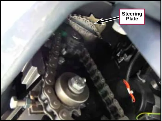 Photo looking up into the machine showing the steering plate on top of the drive wheel assembly with the roller chain running around it