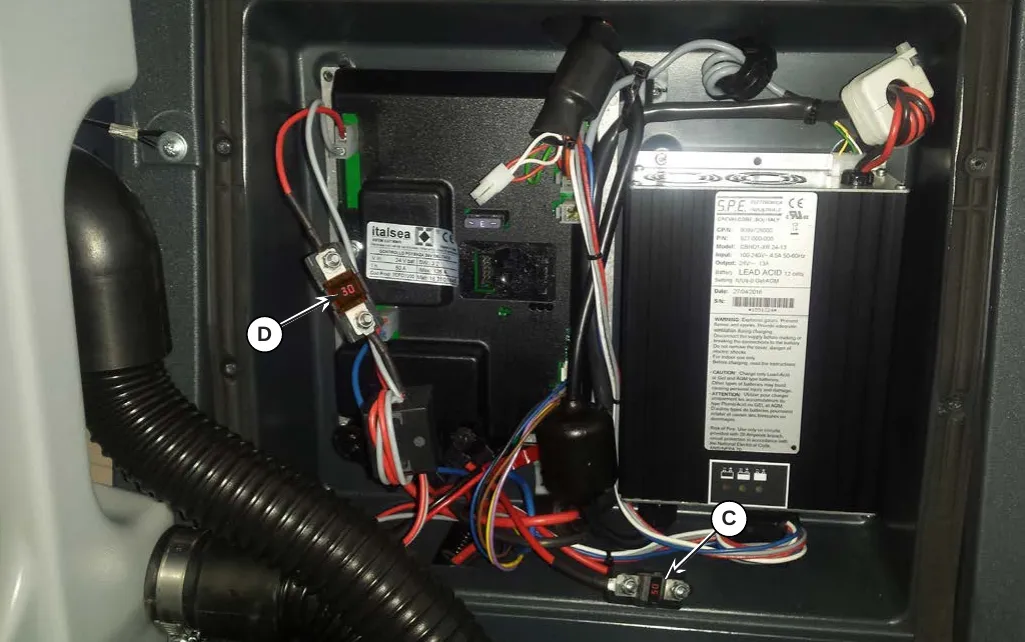 Photo inside the electronic component compartment with arrow C pointing to the brush motor fuse and arrow D pointing to the drive system motor fuse