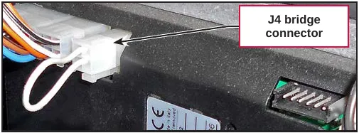 Photo of the J4 bridge connector, a white plug with a looped wire, installed on the main machine controller