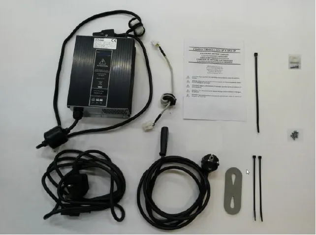 Battery charger kit parts laid out: charger, power cords for UK and EU, cable ties, instruction sheet, bracket and hardware