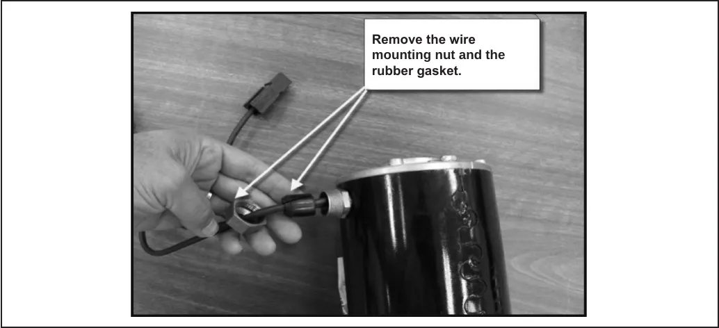 Photo of the motor on a workbench with a hand holding the wire mounting nut and rubber gasket; callout text reads: Remove the wire mounting nut and the rubber gasket.