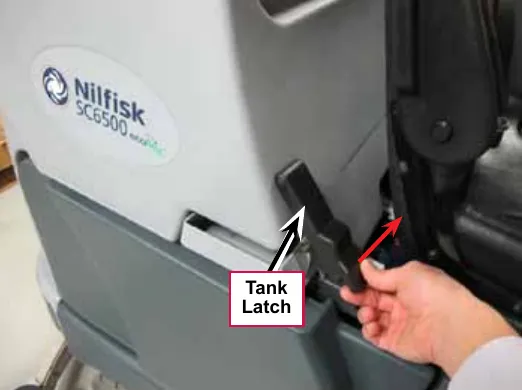 Photo of a hand releasing the Tank Latch on the side of the machine below the Nilfisk SC6500 label; a red arrow shows the pull direction