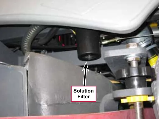Photo underneath the left side of the machine with a callout and arrow pointing to the Solution Filter