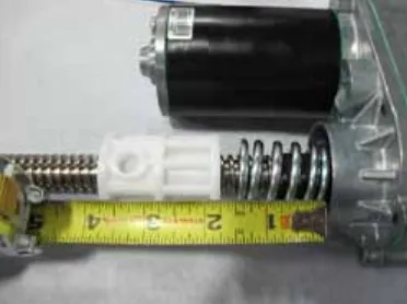 Photo of the actuator with a tape measure showing the drive nut about 1 3/4 in from the motor housing in the retracted position