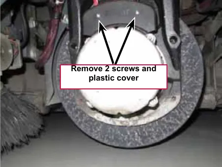 Photo of the front drive wheel with the motor facing forward; arrows point to the two screws and the plastic cover to remove