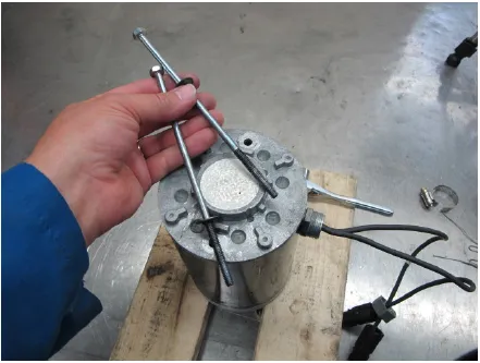 Photo of a hand holding the two long through bolts above the motor after removing them.