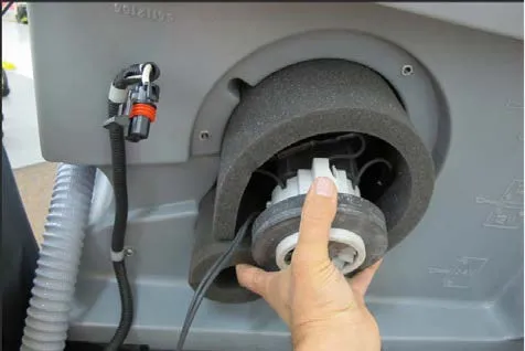 Hand holding the vacuum motor as it is pulled out of its foam sleeve in the housing