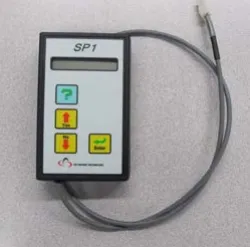 Photo of the PGDT programmer, a handheld unit labeled SP1 with four buttons and a cable