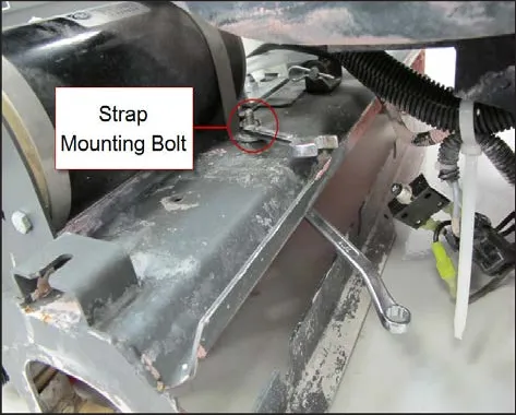 Motor strap on the brush head with a wrench on the strap mounting bolt, which is circled and labeled Strap Mounting Bolt