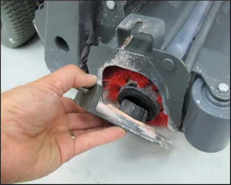 A hand holding the idler cover against the end of the brush head with the idler pulley in the brush end