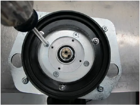 Photo of a drill with a screwdriver bit removing one of the four screws holding the brush motor to the motor plate.