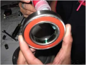 Photo of a hand holding the bearing while retaining compound is applied to its inner race.