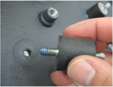 Photo of a hand holding an isolator whose threads are coated with blue threadlocker.