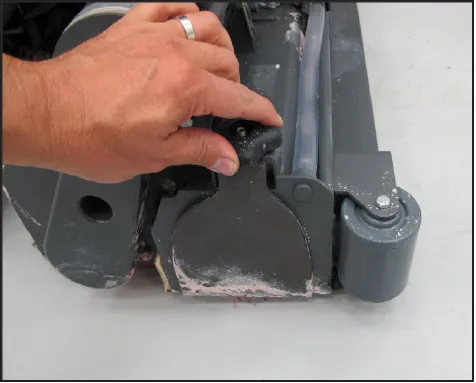 A hand loosening the hand wheel nut on the idler cover at the end of the brush head