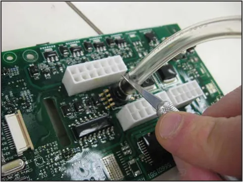 Hand using a small knife to cut the clear pressure tube off next to the sensor on the circuit board