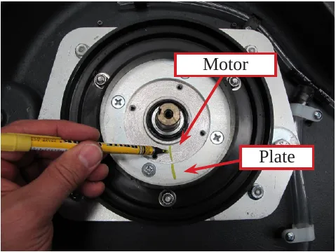 Photo of a marker drawing an alignment mark across the brush motor and the motor plate, with arrows labeled Motor and Plate.