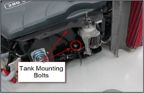Photo of the lower rear of the tank with arrows from the label Tank Mounting Bolts to two mounting bolts