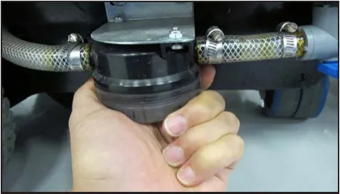 Photo of a hand holding the solution filter bowl and cover below the hoses