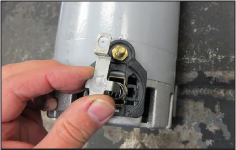 Photo of a hand pulling the brush and spring assembly out of the brush holder.