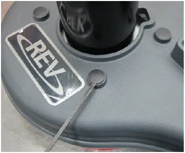 Photo of the top of the scrub head with a tool lifting a plastic cover over an isolator nut.