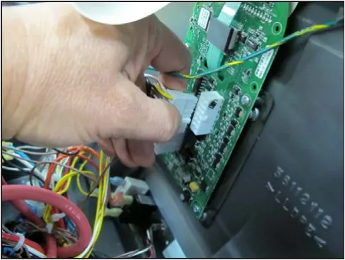 Hand unplugging a connector from the main machine controller circuit board