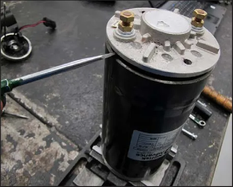 A screwdriver prying at the seam of the motor endplate on the motor casing