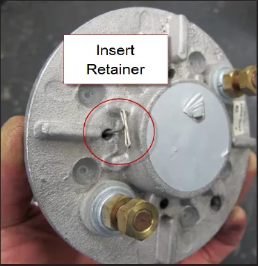 Outside of the end cover with a retaining wire inserted through the access hole, circled and labeled Insert Retainer