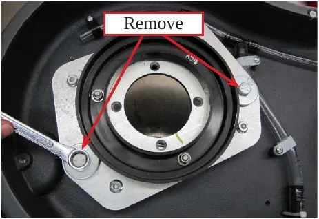 Photo inside the deck with a wrench on a retaining bolt and arrows labeled Remove pointing to the retaining bolts.