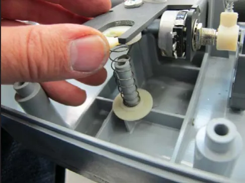 Photo of a hand holding the paddle centering spring stack beside the potentiometer after the screw is removed