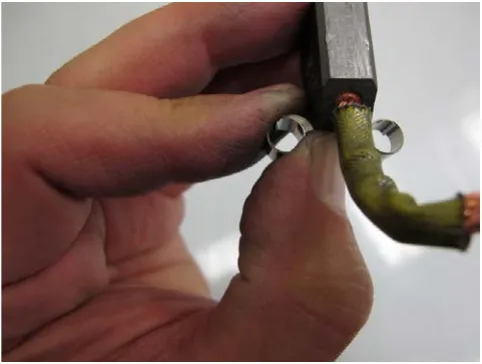 Photo of a carbon brush being seated in the cup of the spring.