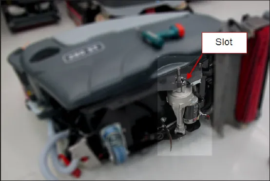 Photo of the machine laid on its side with the transaxle visible and an arrow labeled Slot pointing to the frame slot