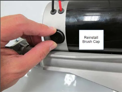 Photo of a hand tightening the round black brush cap, labeled Reinstall Brush Cap