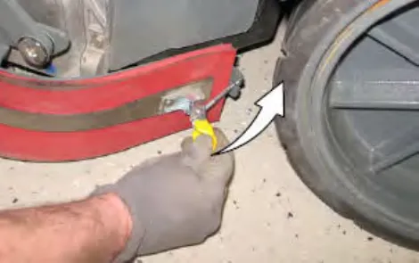 Hand unhooking the retaining band latch from the side squeegee assembly, with an arrow showing the direction