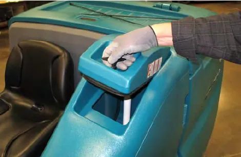 A gloved hand twisting the solution tank cover handle to open the cover