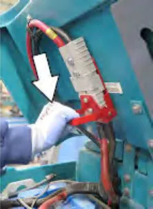 Hand pulling down the battery quick-disconnect connector, with an arrow pointing down