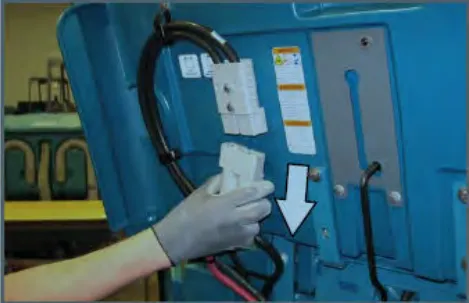 Hand pulling down the battery side cable connector, with an arrow pointing down