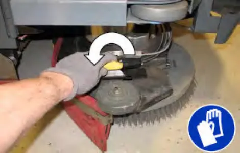 Hand loosening the side brush squeegee assembly handle, with a curved arrow showing the direction, plus glove symbol