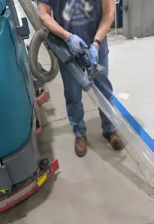 Operator holding the live wand and hose beside the machine