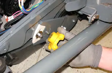 Hand loosening the yellow left brush arm knob