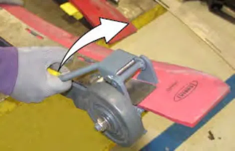 Hand loosening the front retainer latch, with an arrow showing the direction