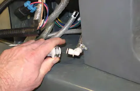 Hand pressing the connector button to disconnect the outlet hose from the ec-H2O manifold