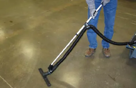 Operator vacuuming the floor with the wet vacuum wand and hose