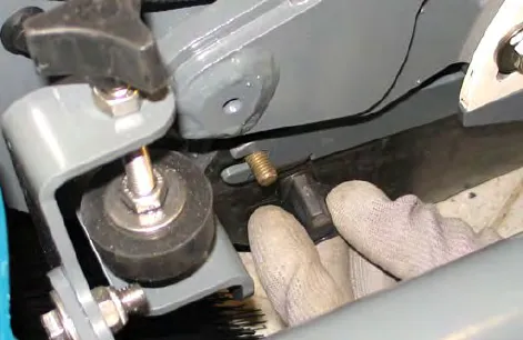 Hand removing one of the three knobs holding the Pre-Sweep side skirt and side skirt plate