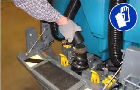 A gloved hand pulling the vacuum hose off the rear squeegee, with a glove-required symbol