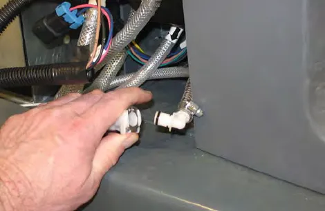 Hand pressing the connector button to disconnect the outlet hose from the ec-H2O manifold