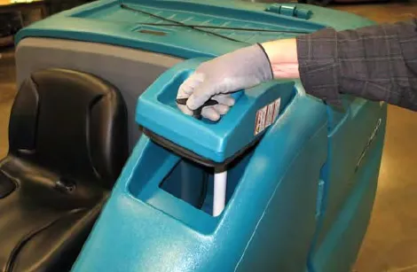 A gloved hand twisting the solution tank cover handle to open the cover
