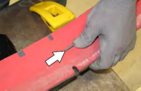 Hand hooking the holes in the squeegee blade onto the tabs, with an arrow pointing to a tab