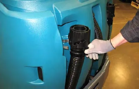 A hand inserting the drain hose into the clip on the side of the solution tank