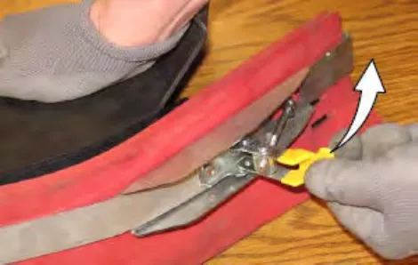 Hand loosening the retaining band latch, with an arrow showing the direction