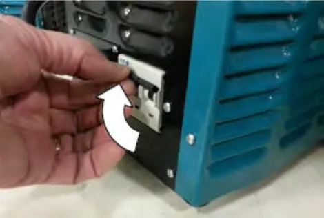 Hand switching on the battery charger breaker, with an arrow showing the direction